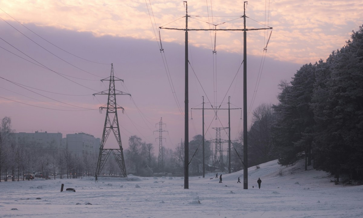 Elektriciteitsmasten en stroomkabels boven een besneeuwd landschap bij Riga.
